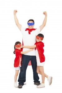 superhero daughters hug father waist. isolated on white background